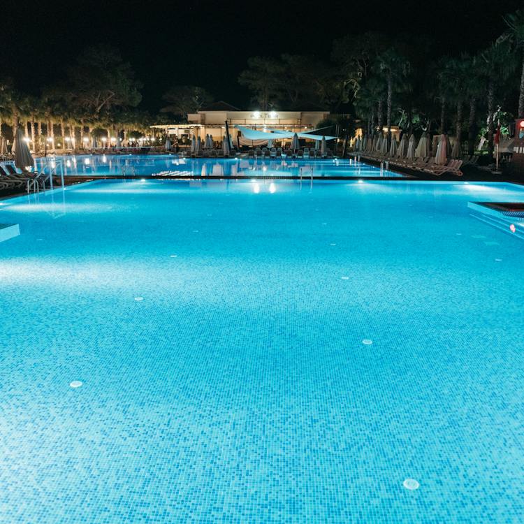 A tranquil swimming pool reflects the surroundings, creating a serene atmosphere. swimming pool contractors in dubai. ideallandscapers.com